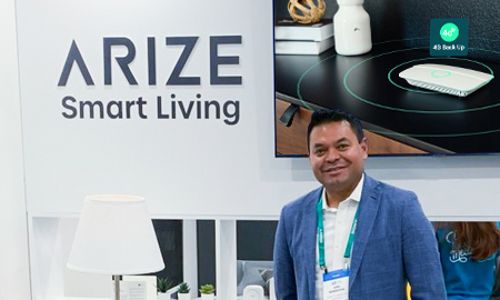 Joel Sandoval, Arize's National Director of Sales, posing in front of a smart tech demo booth.